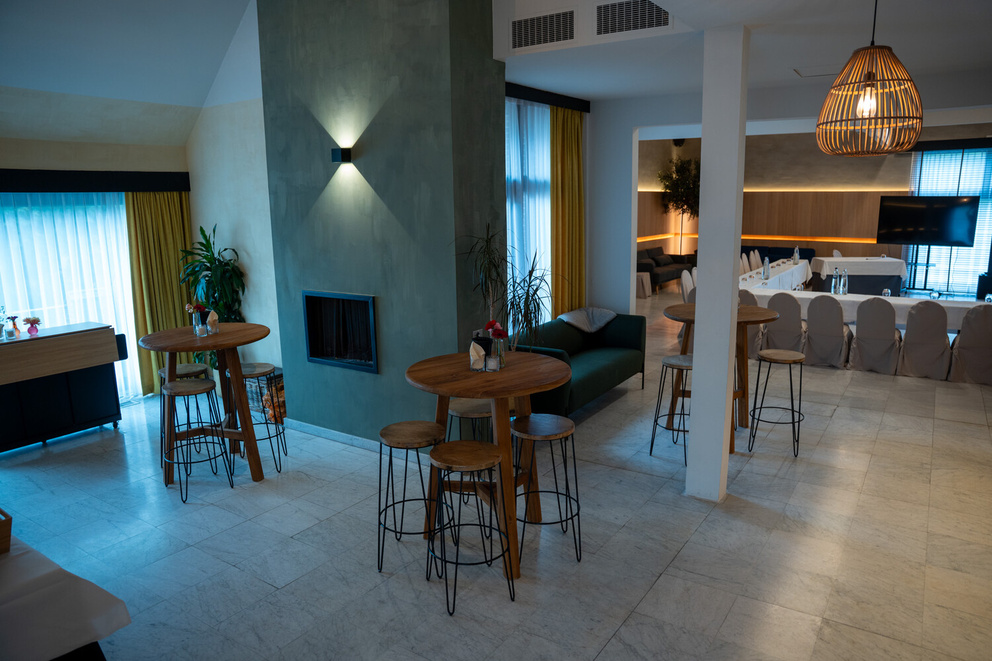 Moderne interieur met houten barretjes, groene muren en een sfeervolle zithoek in een lichte ruimte.