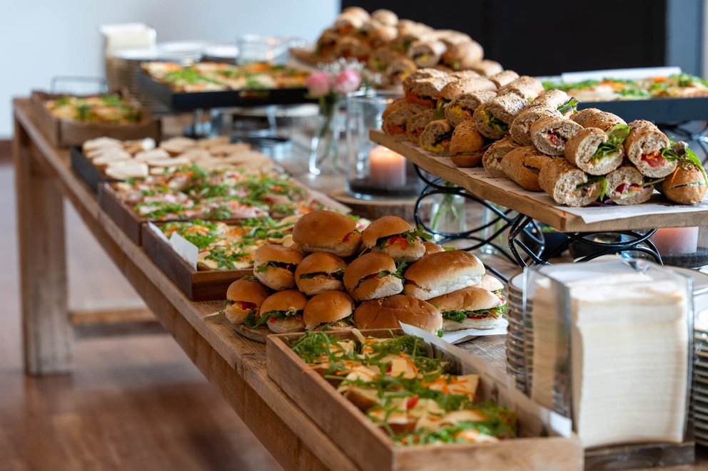 Een prachtig gedekte tafel met verschillende soorten sandwiches, hapjes en salades, perfect voor een buffet.