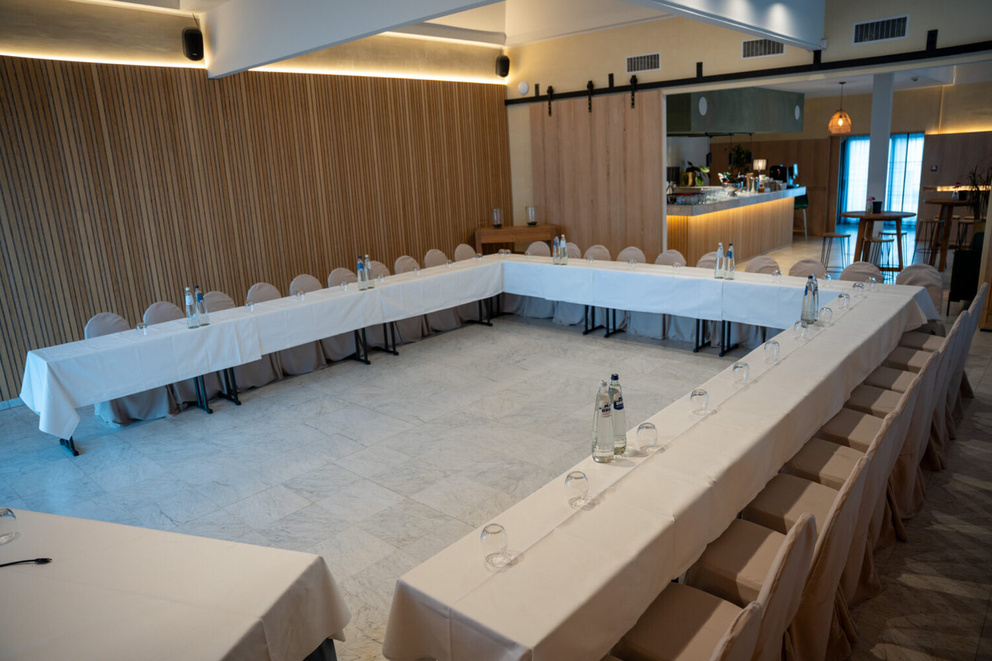 Een stijlvolle vergaderruimte met een U-vormige tafelopstelling en houten wandaccenten.