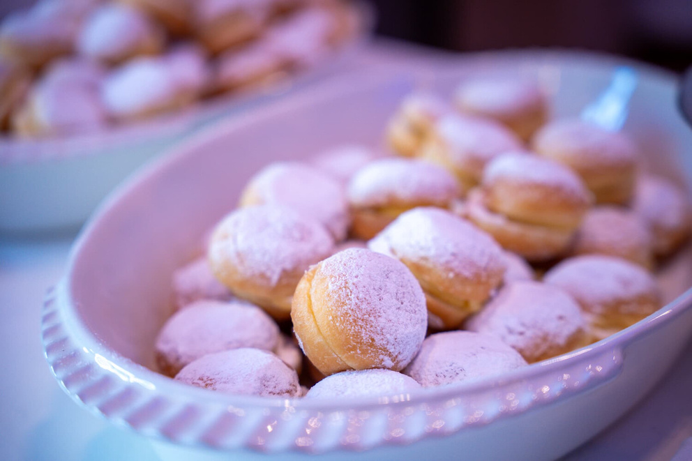 Gele ronde gebakjes met poedersuiker op een wit dienblad, geserveerd op een tafel.