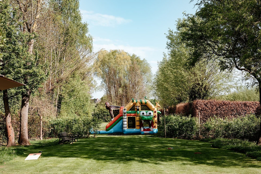 Grote luchtkussen in een groene tuin omringd door bomen en struiken, met blauwe lucht op de achtergrond.