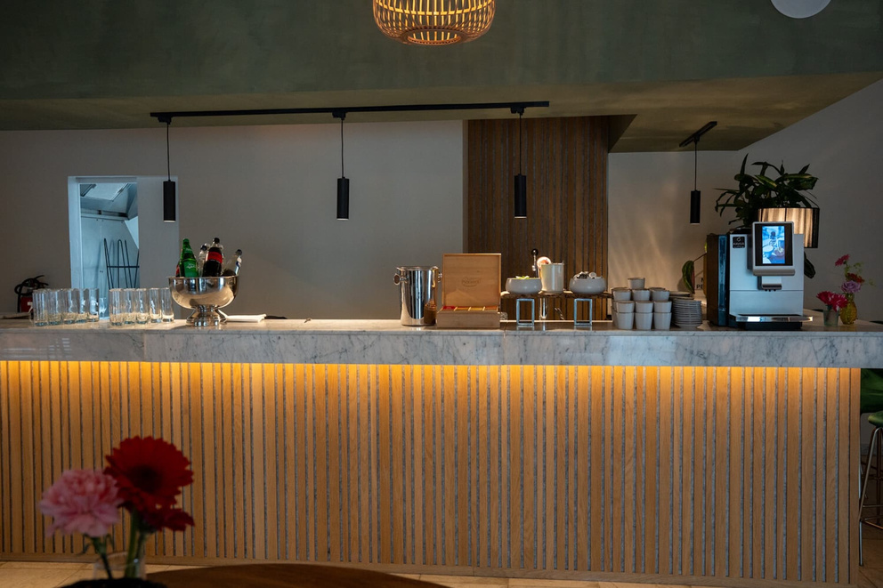 Moderne bar met marmeren toonbank, glazen, drankjes en stijlvolle verlichting in een sfeervolle inrichting.